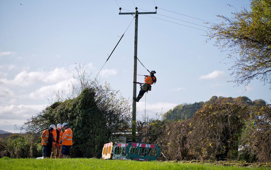WPD linesman climbing pole in a field