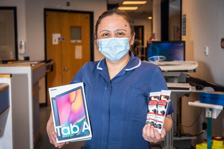 NHS worker holding iPad and hand cream wearing face mask