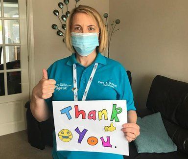Care worker in mask holding thank you sign