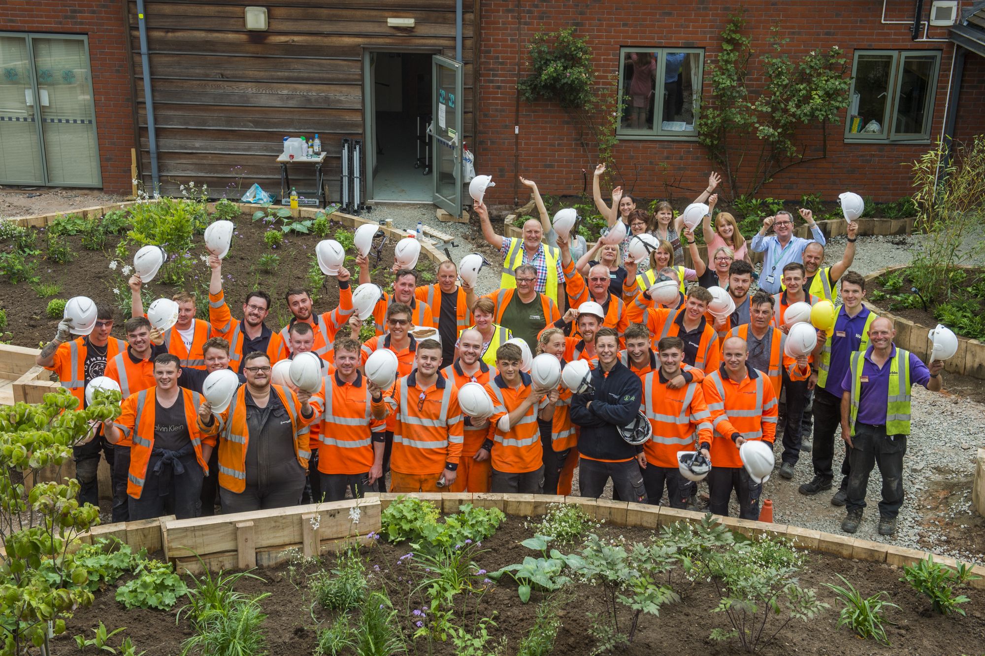 All workers waving at camera from garden