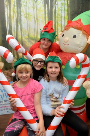 Children dressed as elves with Christmas candy canes in front of a forest background