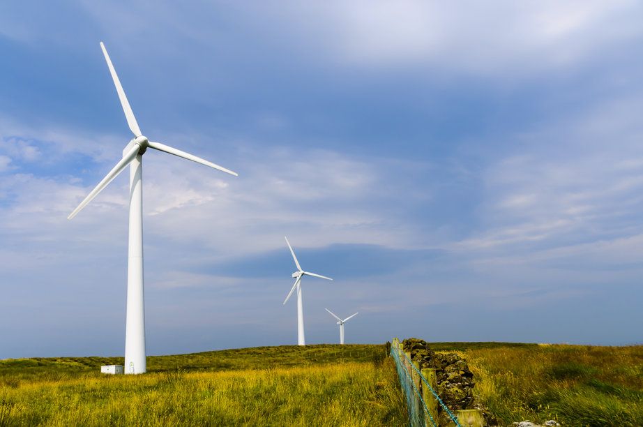 Three wind turbines in a field against blue sky