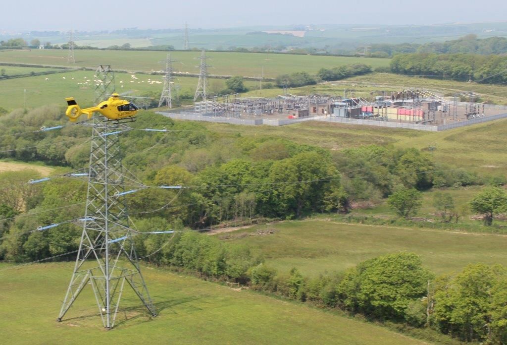 WPD helicopter flying over pylon in countryside